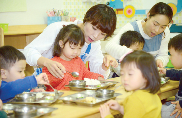 기자가 수저 사용이 서툰 아이들을 위해 점심식사를 도와주고 있다.