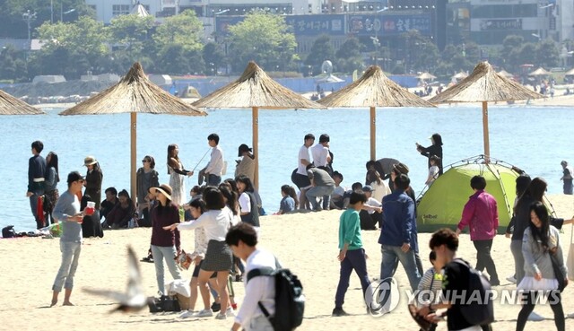 ▲ 징검다리 연휴이자 부처님 오신날인 3일 오후 부산 광안리해수욕장에서 나들이객들이 갈대 파라솔 아래에서 더위를 식히며 휴일을 만끽하고 있다.  /연합
