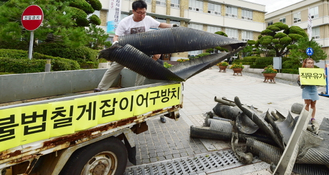 ▲ 28일 오전 인천시 중구 중구청 앞에서 인천녹색연합 회원들이 중구 영종도 서쪽 갯벌(용유해변)에서 수거한 칠게잡이 불법 어구를 내던지며 어구 철거를 촉구하는 퍼포먼스를 하고 있다.장용준기자