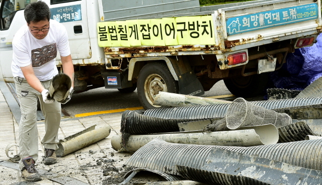 ▲ 28일 오전 인천시 중구 중구청 앞에서 인천녹색연합 회원들이 중구 영종도 서쪽 갯벌(용유해변)에서 수거한 칠게잡이 불법 어구를 내던지며 어구 철거를 촉구하는 퍼포먼스를 하고 있다.장용준기자