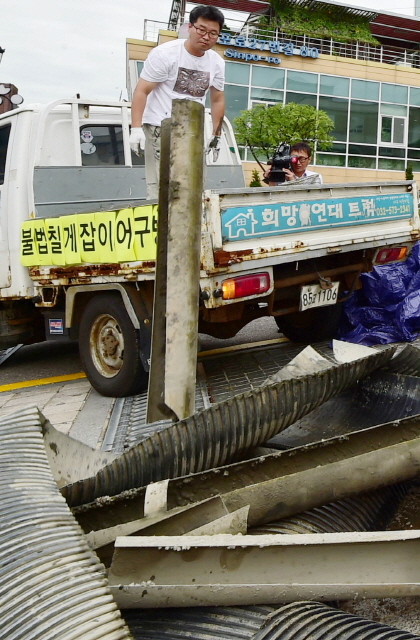 ▲ 28일 오전 인천시 중구 중구청 앞에서 인천녹색연합 회원들이 중구 영종도 서쪽 갯벌(용유해변)에서 수거한 칠게잡이 불법 어구를 내던지며 어구 철거를 촉구하는 퍼포먼스를 하고 있다.장용준기자