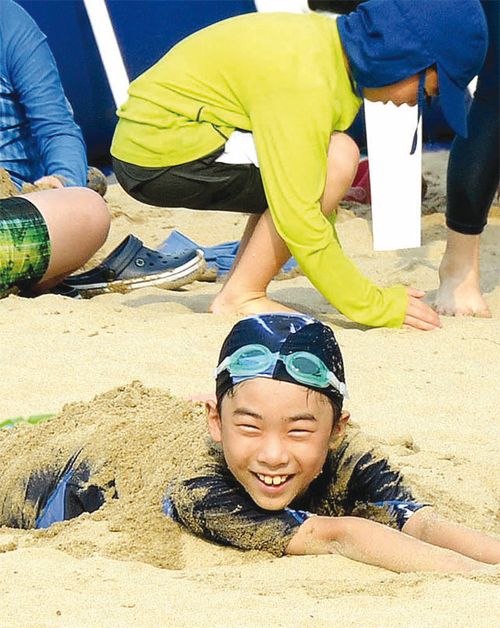 비치 파라솔과 함께 설치된 인공 백사장에서 아이들이 동심어린 모래장난을 하고 있다.