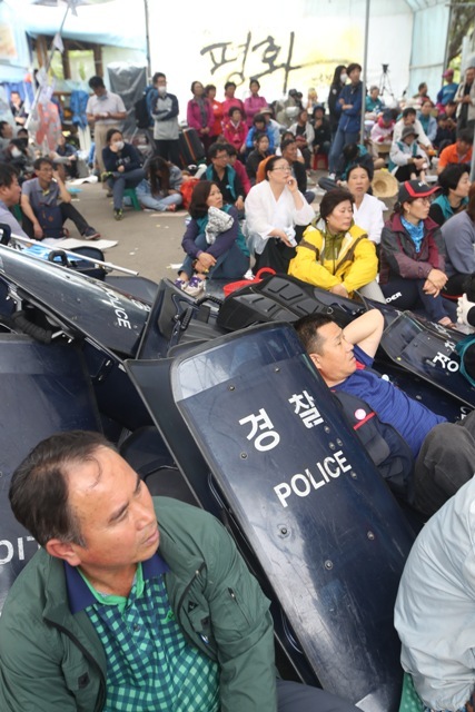 ▲ 사드(THAAD·고고도미사일방어체계) 잔여 발사대 4기 추가배치가 시작된 7일 오전 관련 장비를 실은 미군 차량이 사드 기지(옛 성주골프장)로 들어가자 사드배치에 반대하는 주민들이 성주군 초전면 소성리 마을회관 앞에 앉아 있다.  /연합