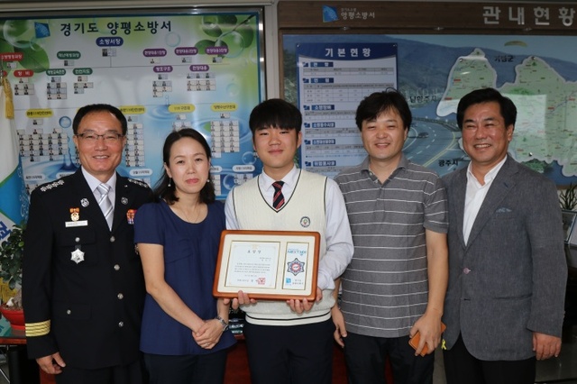 ▲ 소방영웅을 축하하는 자리에 선 수상자와 가족들 좌로부터 신민철서장,어머니 이은숙씨 정민기군,아버지 정태환씨 , 황일수 서종중 교감