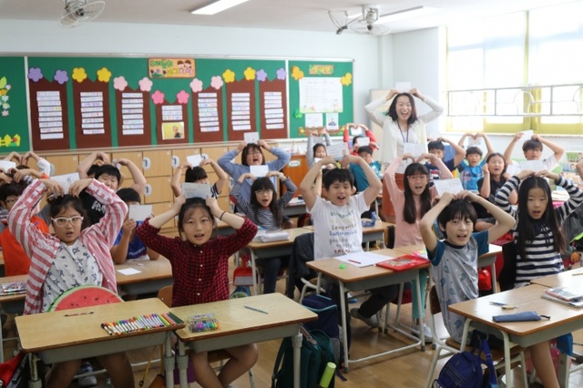 ▲ 양평초등학교 4학년1반 어린이들과 김영민교사가 국군장병에게 쓴 위문편지를 들고 사랑의 하트를 만들어 보이고 있다.