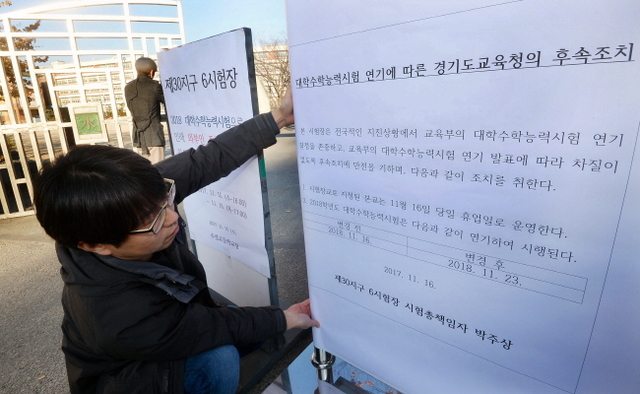 ▲ 경북 포항에서 발생한 규모 5.4 규모의 강진으로 2018학년도 대학수학능력시험이 일주일 연기된 16일 수원 수성고등학교에서 교직원들이 수능 연기 안내문을 부착하고 있다. 조태형기자