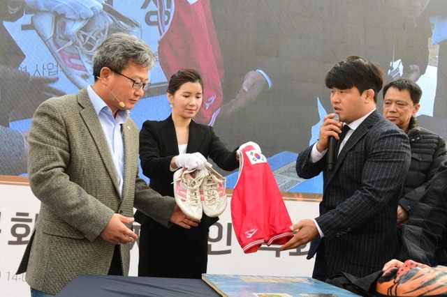 ▲ 22일 열린 ‘화성시 문화예술체육인 특화묘역 성공기원식’에서 LA올림픽 레슬링 올림픽리스트 고(故) 김원기 선수의 가족이 시합복과 레슬링화 등 유품을 채인석 시장에게 전달하고 있다.화성시 제공