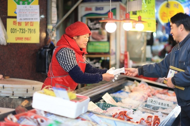 ▲ 시민이 성남사랑상품권을 이용해 전통시장에서 먹거리를 사고 있다. 사진=성남시 제공