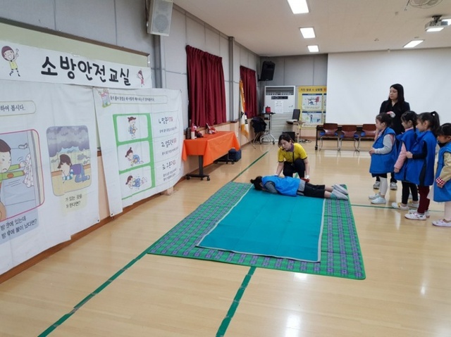 ▲ 성남 관내 초등학교 1학년생들이 소방안전체험 중 하나인 화재 때 옷에 불이 붙은 경우 대처 방법을 실습 중이다. 사진=성남시 제공