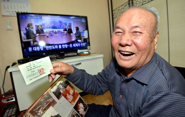 ▲ 판문점에서 남북정상회담이 열린 27일 수원시 영통구 매탄동 자택에서 TV로 정상회담을 지켜보던 남북이산가족 원형기씨가 이산가족 방문신청서 영수증을 들어 보이며 환하게 웃고 있다. 판문점공동취재단=전형민기자