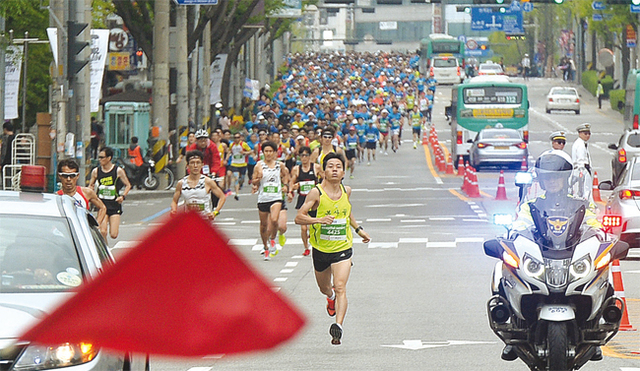 10km코스 참가 선수들이 도심을 배경으로 장안로터리를 향해 힘차게 달려오고 있다.
