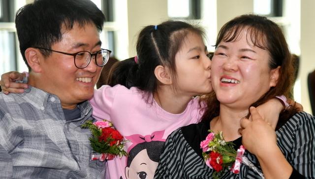 ▲ 어버이날인 8일 곽재영, 오경란 부부가 약 7년전 입양한 딸 곽빛나로부터 카네이션과 뽀뽀를 선물 받으며 환하게 웃고 있다. 곽씨부부는 