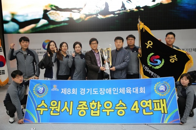 ▲ 12일 물맑은양평체육관에서 열린 제8회 경기도장애인체육대회 시상식서 종합우승 4연패를 달성한 수원시 선수단이 우승기와 플래카드를 펼쳐들고 기념촬영을 하고 있다.경기도장애인체육회 제공