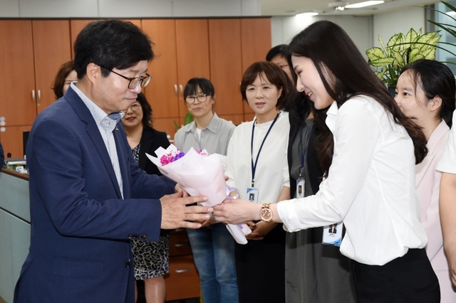 부서를 방문한 염태영 수원시장에게 수원시 공직자가 꽃다발을 건네고 있다.