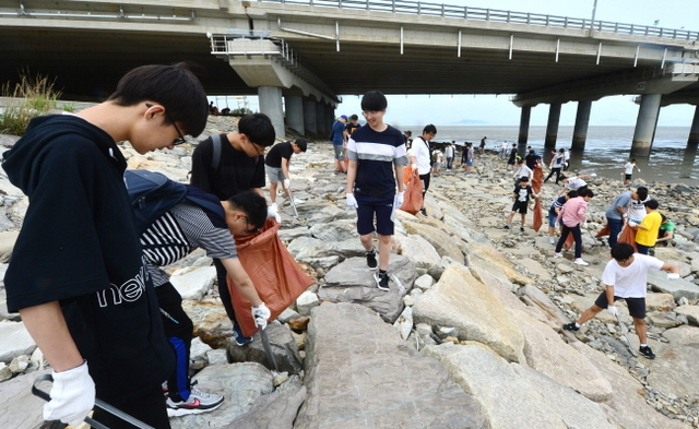 ▲ 바다의 날을 이틀 앞둔 29일 오후 인천시 중구 인천대교기념관 앞 해안에서 환경단체 회원들과 학생들이 쓰레기를 수거하고 있다.장용준기자