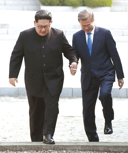 문재인 대통령(오른쪽)과 북한 김정은 국무위원장(왼쪽)이 4월 27일 오전 판문점에서 손을 잡고 군사분계선을 넘는 모습.