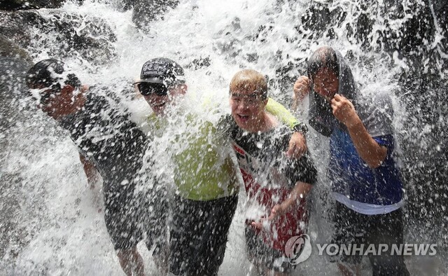 폭염이 계속된 21일 경남 함양군 마천면 음정마을 비리내 폭포를 찾은 피서객들이 폭포수를 맞으며 무더위를 식히고 있다. 연합뉴스