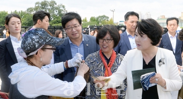 고정숙 여사가 7일 화성행궁 광장에서 열린 2018 수원한국지역도서전을 방문해 염태영 수원시장, 관계자들과 함께 다양한 부스들을 둘러보던 중 가죽 제품을 구매하고 있다. 조태형기자