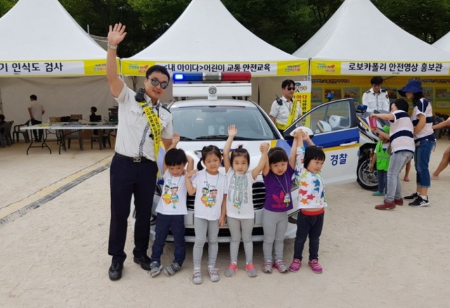 ▲ 안양동안경찰서 관계자가 제4회 안양시민안전 페스티벌에 참여한 아이들과 함께 교통안전교육 홍보부스 앞에 배치된 경찰차 앞에서 기념촬영을 하고 있다.