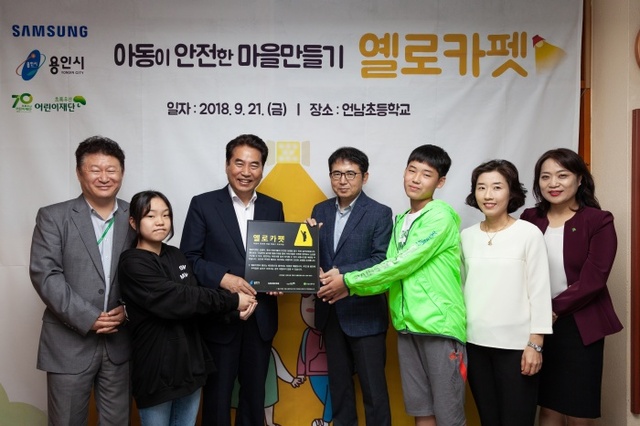 ▲ 삼성전자 DS부문 및 초록우산어린이재단 경기지역본부 관계자들이 지난 21일 옐로카펫 현판 전달식을 진행했다. 왼쪽부터 강원화 언남초등학교장, 언남초등학교 학생부회장, 백군기 용인시장, 김선식 삼성전자 DS부문 사회봉사단장, 언남초등학교 학생회장, 언남초등학교 학부모회장, 진용숙 초록우산어린이재단 경기지역본부장
