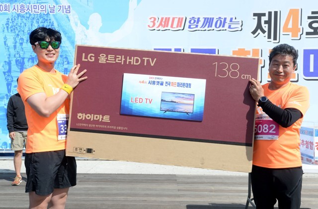▲ 제4회 시흥갯골 전국하프마라톤대회’가 열린 7일 시흥 배곧생명공원 잔디광장에서 1등 경품 당첨자(왼쪽)가 김준연 시흥시체육회장과 기념촬영을 하고 있다.조태형기자