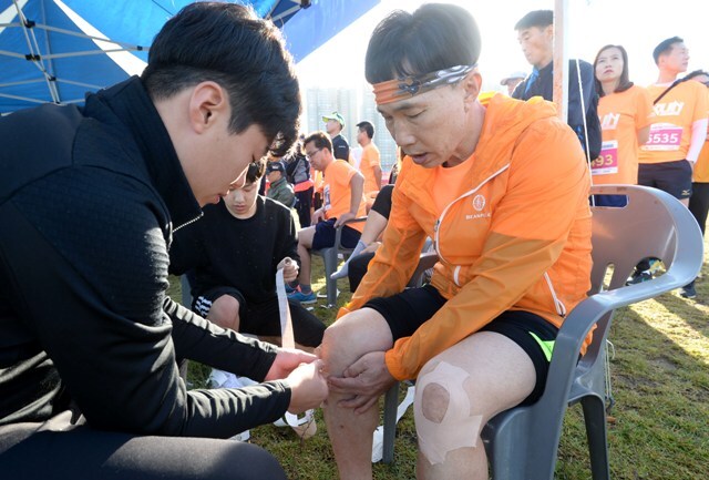 ▲ 제4회 시흥갯골 전국하프마라톤대회’가 열린 7일 시흥 배곧생명공원 잔디광장에서 참가자들이 출발에 앞서 스포츠 테이핑을 받고 있다.조태형기자