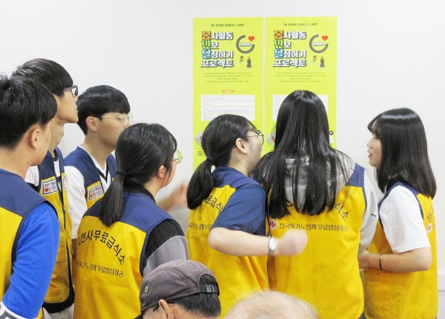 ▲ 사진3 급식소에 부착된 봉만달포스터를 보고있는 자원봉사자들