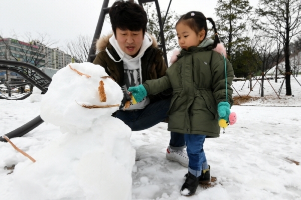 수도권 지역에 첫 눈이 내린 24일 의정부시내에서 한 어린이가 부모님과 함께 눈사람을 만들고 있다. 조태형기자
