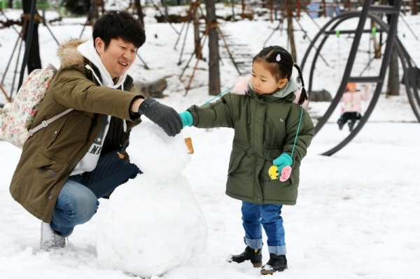 수도권 지역에 첫 눈이 내린 24일 의정부시내에서 한 어린이가 부모님과 함께 눈사람을 만들고 있다. 조태형기자