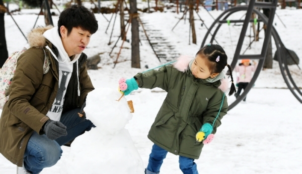수도권 지역에 첫 눈이 내린 24일 의정부시내에서 한 어린이가 부모님과 함께 눈사람을 만들고 있다. 조태형기자