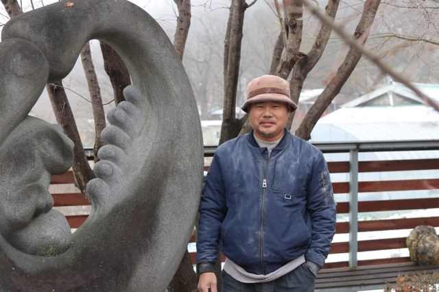 김태규 작가가 작업중에 잠시 시간을 내 그의 집 마당에 놓인 작품앞에서 사진을 찍고 있다.