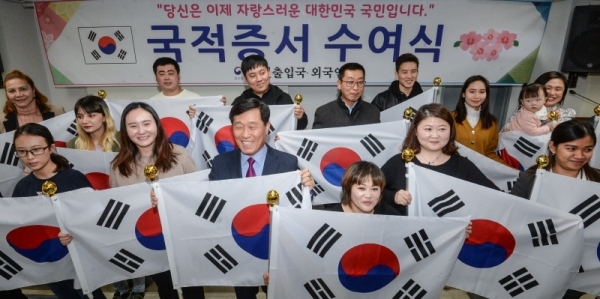 22일 오후 인천 중구 인천출입국외국인청에서 열린 '국적증서 수여식'에서 귀화인들이 대한민국 국적증서를 받은 뒤 태극기를 들고 기념촬영을 하고 있다.조주현기자