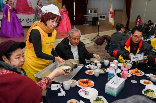 29일 오전 수원시 영통구청 대회의실에서 열린 ‘어르신 孝 떡국잔치’에서 대한적십자사 경기도지사 자원봉사자들이 어르신들에게 떡국을 대접하고 있다. 삼성전기 후원으로 수원시내 소외계층 어르신과 봉사자 150여 명이 모인 가운데 열린 이번 행사에선 다과와 공연, 선물전달 등이 진행됐다.  윤원규 수습기자