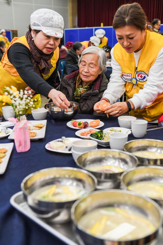 29일 오전 수원시 영통구청 대회의실에서 열린 ‘어르신 孝 떡국잔치’에서 대한적십자사 경기도지사 자원봉사자들이 어르신들에게 떡국을 대접하고 있다. 삼성전기 후원으로 수원시내 소외계층 어르신과 봉사자 150여 명이 모인 가운데 열린 이번 행사에선 다과와 공연, 선물전달 등이 진행됐다.  윤원규 수습기자