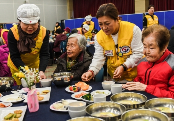 29일 오전 수원시 영통구청 대회의실에서 열린 ‘어르신 孝 떡국잔치’에서 대한적십자사 경기도지사 자원봉사자들이 어르신들에게 떡국을 대접하고 있다. 삼성전기 후원으로 수원시내 소외계층 어르신과 봉사자 150여 명이 모인 가운데 열린 이번 행사에선 다과와 공연, 선물전달 등이 진행됐다.  윤원규 수습기자