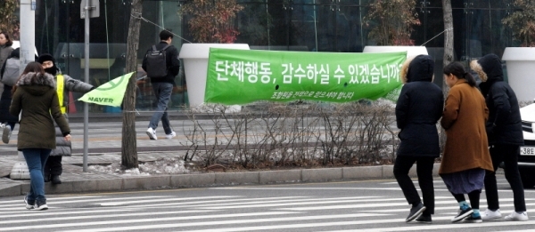 민주노총 화학섬유식품산업노조 네이버지회(네이버 노조)가 20일 성남시 분당구 네이버 본사에서 첫 쟁의행위를 진행했다. 네이버 본사 옆 노조가 걸어둔 현수막을 네이버 직원들과 시민들이 지나치고 있다. 윤원규 수습기자