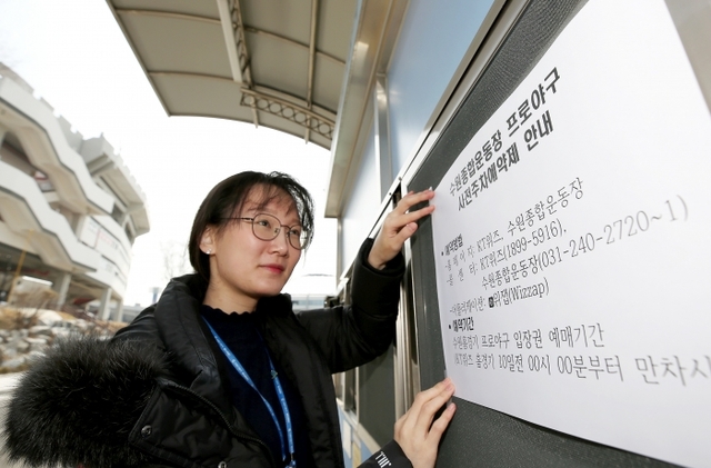 18일 수원도시공사 종합운동장 직원이 남문게이트에 사전주차예약 안내문을 붙이고 있다.