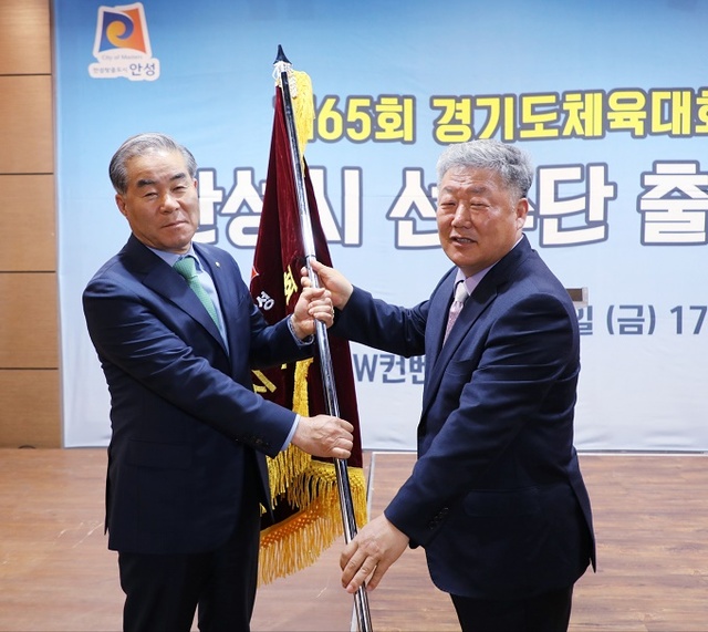 우석제 안성시장(오른쪽)이 제65회 경기도 체육대회 선수단 출정식에서 양승환 부단장에게 단기를 전달하고 있다.