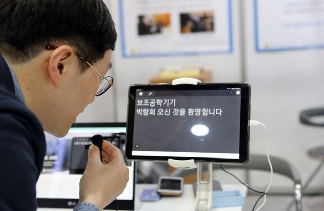 한국장애인고용공단이 22~23일 이틀간 개최한 ‘2019년 제14회 대한민국 보조공학기기 박람회’에서 방문객이 청각장애인에게 문자통역을 해주는 스마트 보조공학기기 ‘소보로 탭 비즈니스’를 시연하고 있다. 한국장애인고용공단 제공