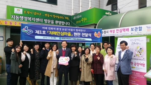 남희숙 수원시 팔달구보건소장(가운데 오른쪽)이 지영호 지동 주민자치위원장에게 ‘제1호 치매안심마을’ 현판을 전달하고, 관계자들과 함께 기념촬영을 하고 있다.