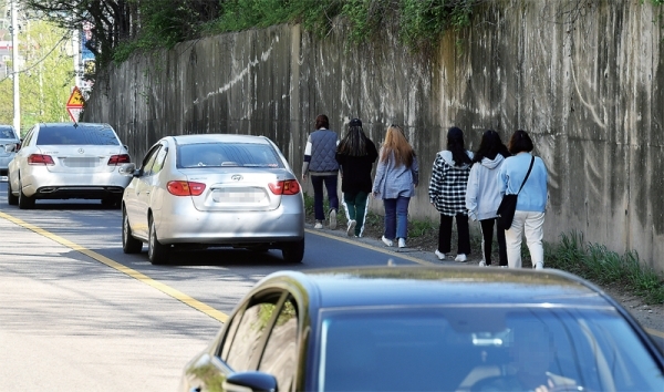 화성시 봉담읍 수원여자대학교 해란캠퍼스 학생들이 지난 3일 버스를 타기위해 인도가 없는 도로변을 아슬아슬하게 걸어가고 있다. 이 학교 관계자는 “학교 입구에서 버스정류장까지 700여m나 되는데 인도가 없다”며 “밤이 되면 하굣길 학생들이 더욱 위험하다”고 말했다. 김시범기자
