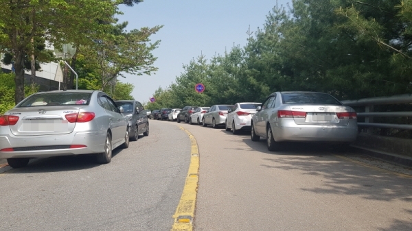 선거관리위원회로 진입하는 도로에 양방향으로 불법 주정차가 돼 있다.
