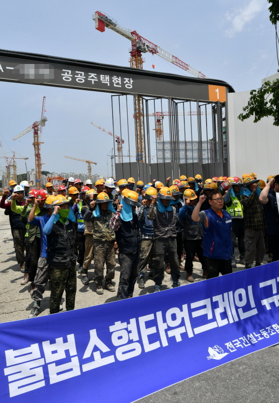 한국노총과 민주노총 소속 전국 타워크레인 노동자들이 4일 오전 3t 미만의 불법 소형타워크레인 규격제한을 요구하며 일제히 파업에 돌입했다. 파업에 돌입한 조합원들이 수원시내 한 공사현장 앞에서 농성을 벌이고 있다. 김시범기자