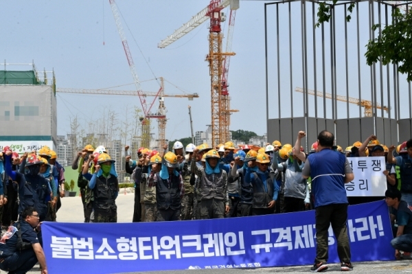 한국노총과 민주노총 소속 전국 타워크레인 노동자들이 4일 오전 3t 미만의 불법 소형타워크레인 규격제한을 요구하며 일제히 파업에 돌입했다. 파업에 돌입한 조합원들이 수원시내 한 공사현장 앞에서 농성을 벌이고 있다. 김시범기자