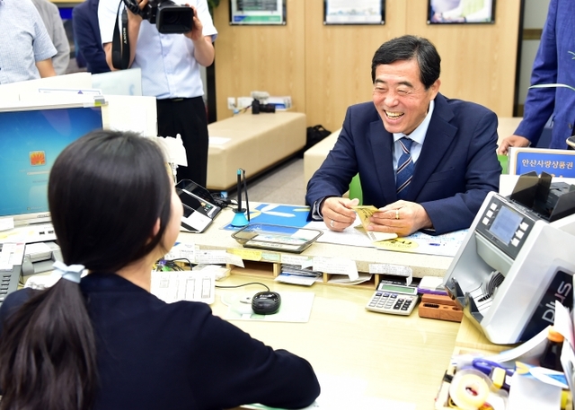 5일 오전 NH 농협 안산시지부에서 열린 다온 판매 50억 원 돌파 기념행사에서 윤화섭 안산시장이 업무를 담당하는 NH농협 직원과 대화하고 있다.