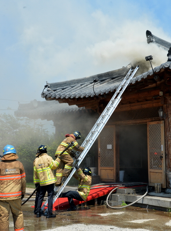 25일 13시 18분께 수원시 권선구 곡반정동의 한 한옥 음식점에서 화재가 발생, 한옥 기와 밑의 공간의 잔불정리를 위해 소방관이 지붕에 올라가고 있다. 윤원규기자