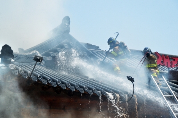 25일 13시 18분께 수원시 권선구 곡반정동의 한 한옥 음식점에서 화재가 발생, 한옥 기와 밑의 공간의 잔불정리를 위해 소방관들이 지붕에 올라가서 작업을 하고 있다. 윤원규기자