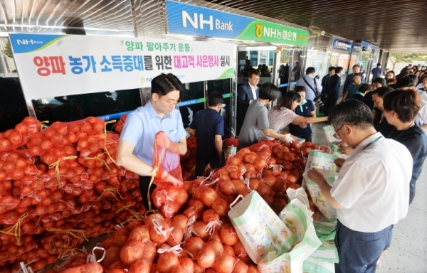 양파값 폭락으로 시름이 깊은 농가를 돕기 위해 25일 오전 경기도청에서 열린 ‘양파 팔아주기 운동’에서 도청 직원과 시민들이 NH농협은행 경기본부가 사은품으로 나눠주는 양파를 받아가고 있다.  윤원규기자
