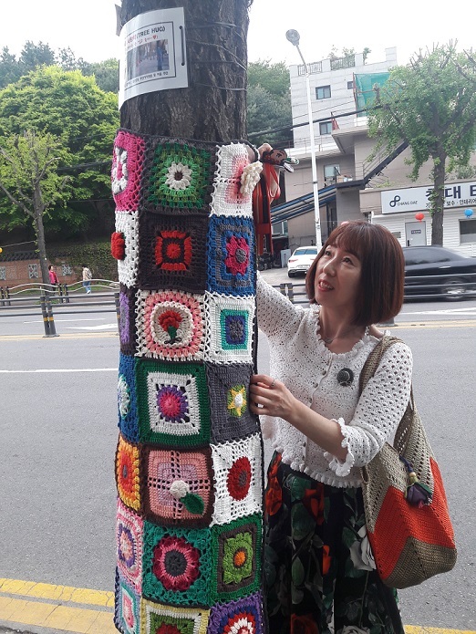 ▲ 광명시 철산2동 한 주민이 직접 만든 뜨개옷을 나무에 입히고 있다. 광명시 제공