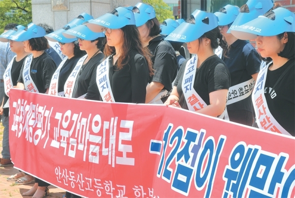 경기도교육청으로부터 자율형사립고(자사고) 지정취소 결정을 받은 안산 동산고등학교 학부모들이 8일 오후 청문회가 열린 수원보훈교육연구원 앞에서 자사고 취소결정에 항의하는 현수막을 들고 침묵시위를 하고 있다. 김시범기자